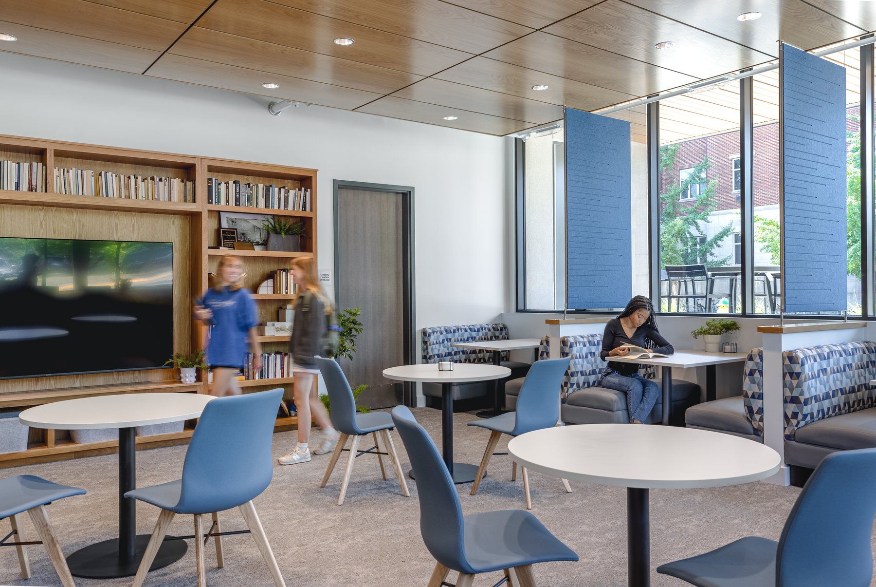 Kentucky University — lounge with round cafe tables, blue chairs, and blue acoustic screens along the window wall