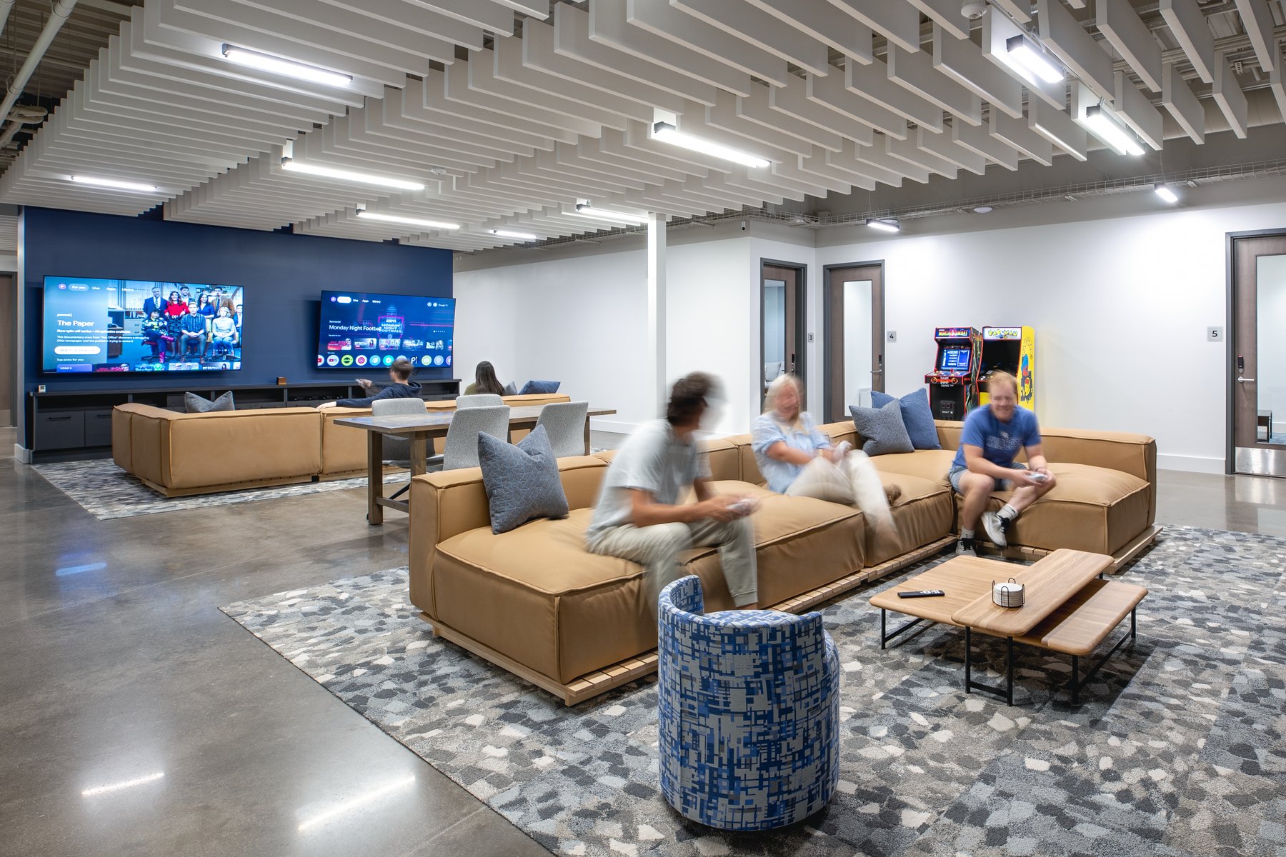 Kentucky University — game room with dual TVs, a tan sectional, and arcade cabinets