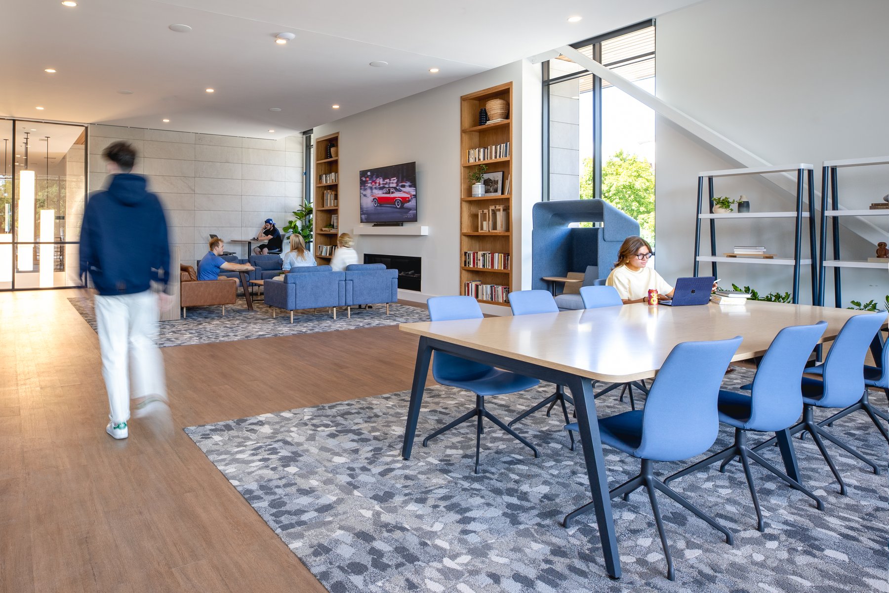 Kentucky University — gathering space with bookshelves, blue sofas, and a long communal table